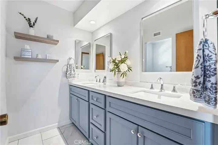 Stylishly updated bathroom showcases a modern dual-sink vanity with quartz-style countertops, custom cabinetry, and contemporary finishes. Clean lines and fresh design create a polished look.