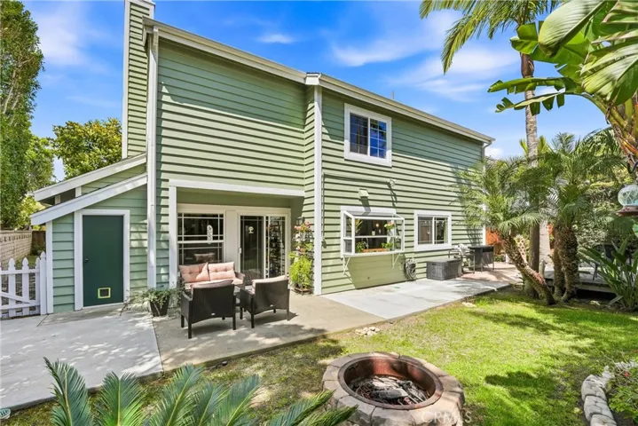 Expansive backyard view highlights the home's attractive exterior, outdoor seating areas, and cozy fire pit. Lush landscaping enhances both privacy and curb appeal.