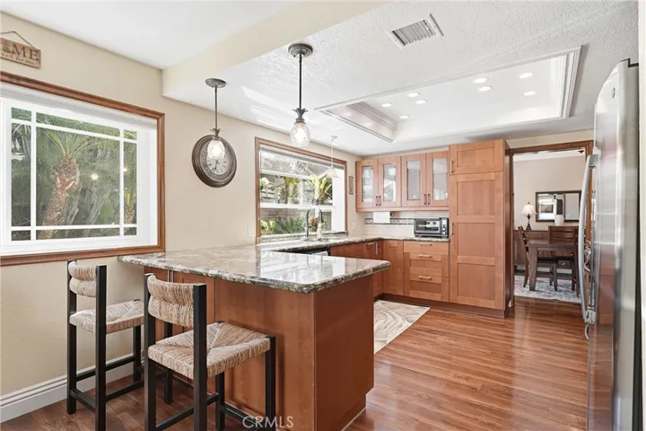 The remodeled kitchen features granite countertops, custom cabinetry, recessed lighting, and a functional breakfast bar for casual dining and conversation.