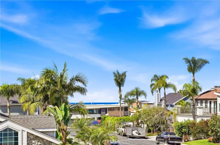 Elevated view captures the surrounding neighborhood, palm-lined streets, and a glimpse of the coastal horizon. A scenic backdrop enhances the home's appeal.