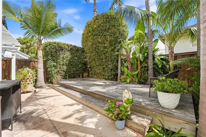Elevated wood deck nestled among lush tropical plantings creates a private setting for outdoor entertaining, dining, or quiet relaxation. Mature palms and greenery provide a resort-inspired atmosphere.
