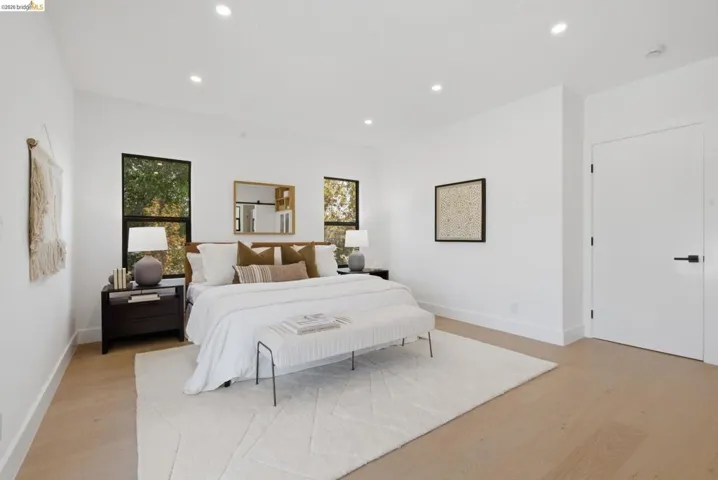 Bright sleeping quarters featuring light wood-finish flooring, recessed lighting, and white walls with contrasting baseboards