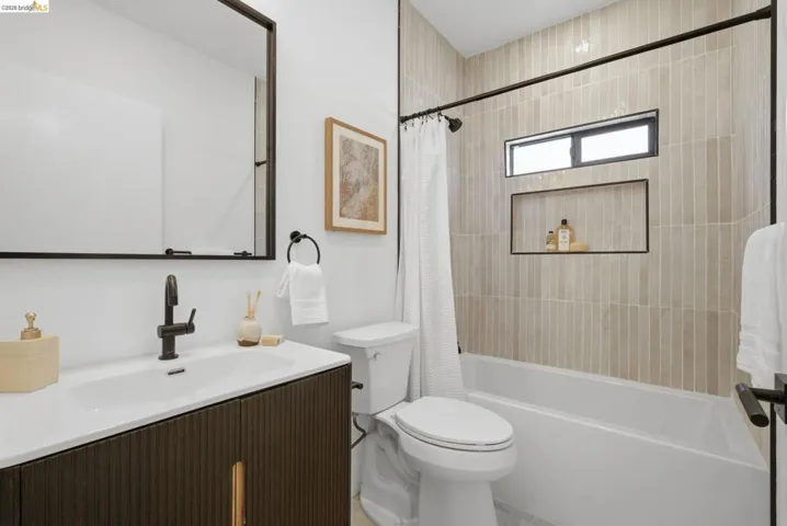 Bathroom featuring a dark wood-finish vanity with a white countertop and integrated sink, matte black fixtures, and a black-framed mirror