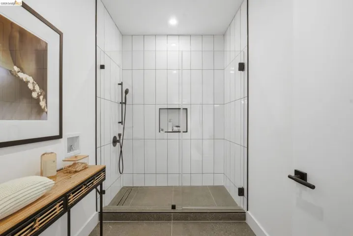 Spacious shower enclosure featuring full-height white vertical subway tile, matte black fixtures, and a recessed niche