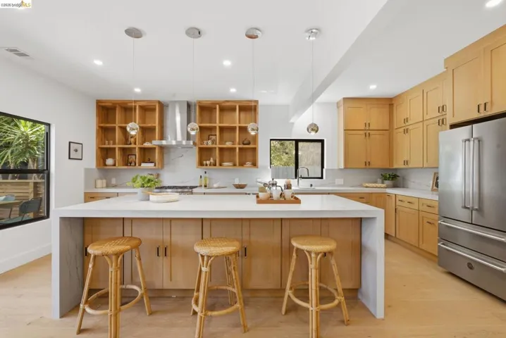 Contemporary kitchen with a central island, light wood-finish cabinetry, stainless steel appliances, and recessed lighting