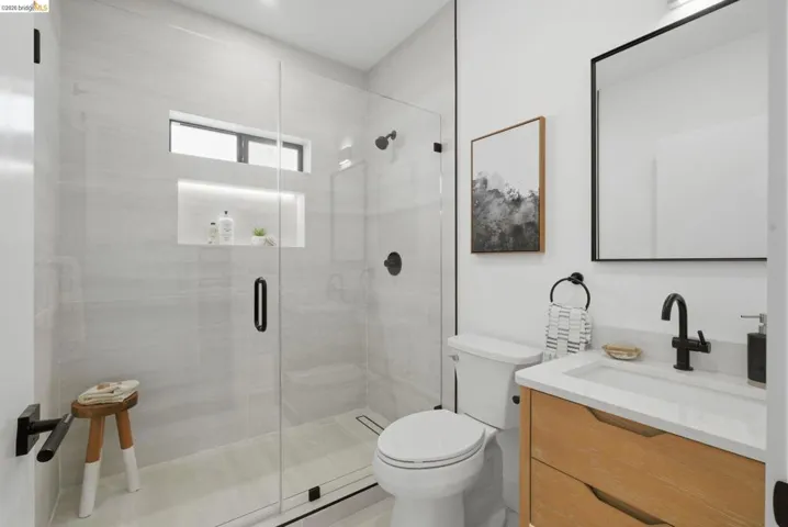 Modern bathroom featuring a glass-enclosed shower with tiled walls and a recessed niche