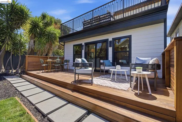 Expansive wood-finish deck with multiple seating areas, offering direct access to the interior via large sliding glass doors