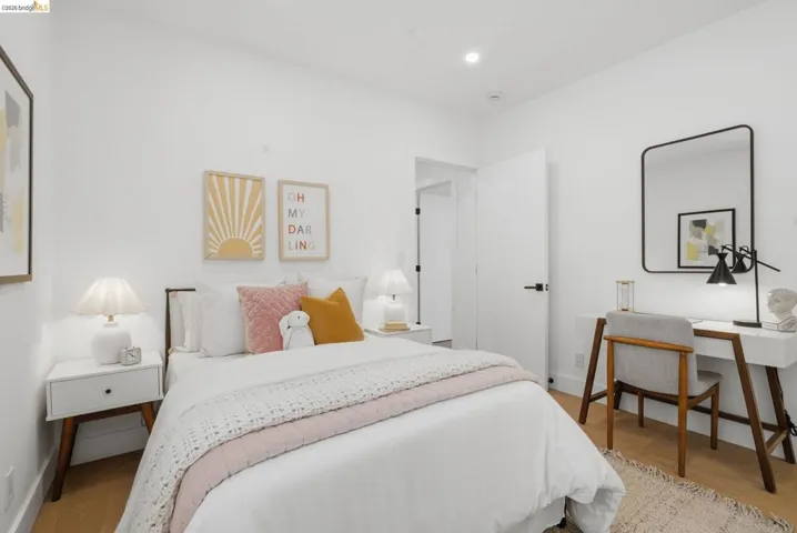 White-painted walls and light wood-finish flooring define this bedroom