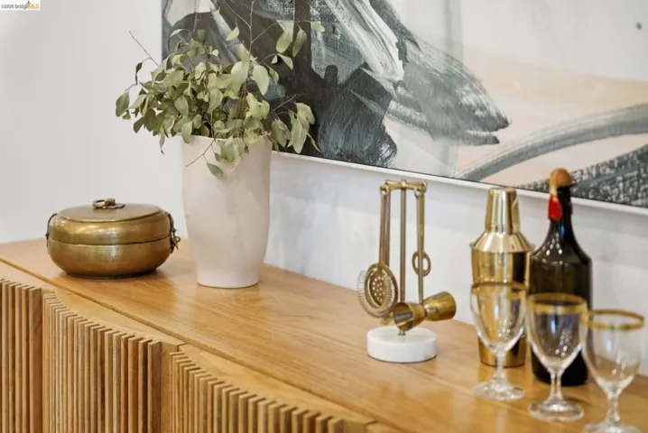 Wood-finish cabinetry featuring slatted door panels, a smooth top surface, and a wall-mounted abstract art piece