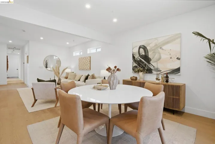 Open-concept interior featuring light wood-finish flooring, recessed lighting, white walls, and high ceilings