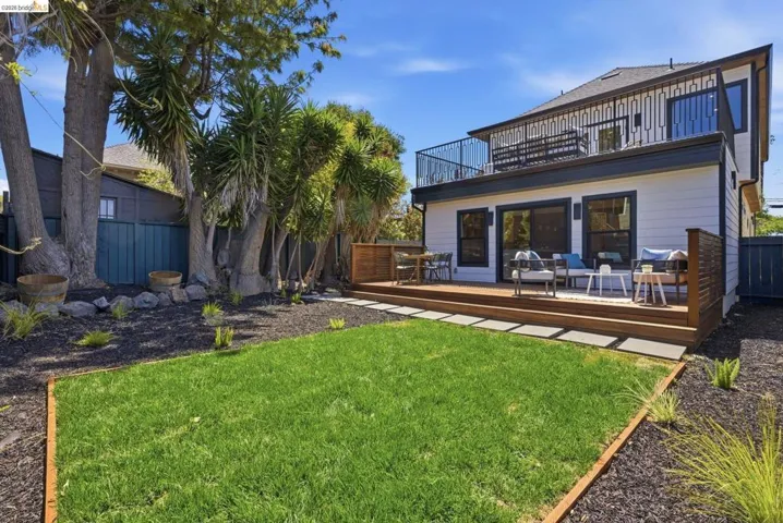 Expansive backyard featuring a manicured lawn, mulched beds, and mature trees