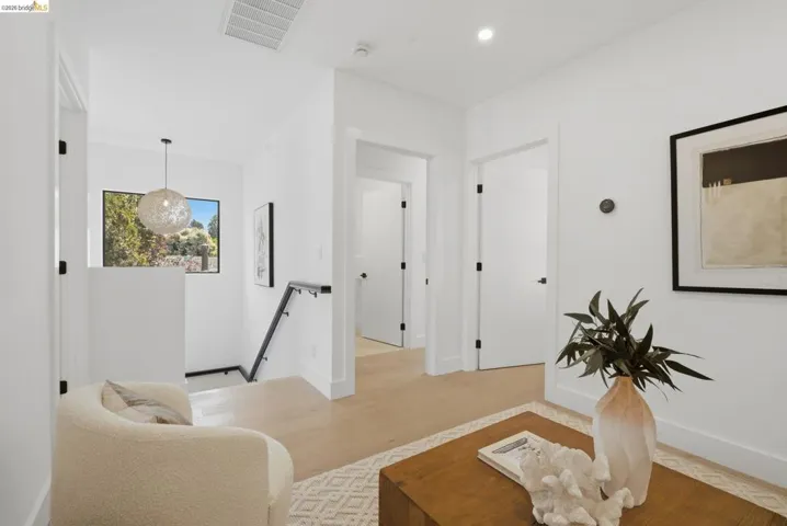Bright hallway featuring light wood-finish flooring, white walls, and contemporary black​​‌​​​​‌​​‌‌​​‌​​​‌‌​​​‌​​‌‌​​‌‌​​‌‌​​​​ hardware