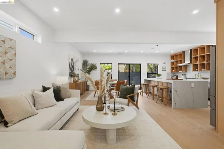 Open-concept living space featuring wood-finish flooring, recessed lighting, and high ceilings