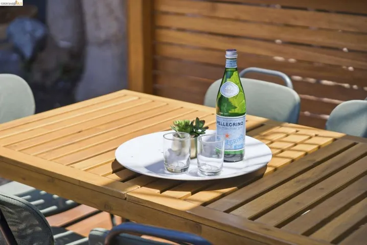 Slatted wood-finish privacy fencing frames an outdoor dining area featuring a slatted wood-finish table