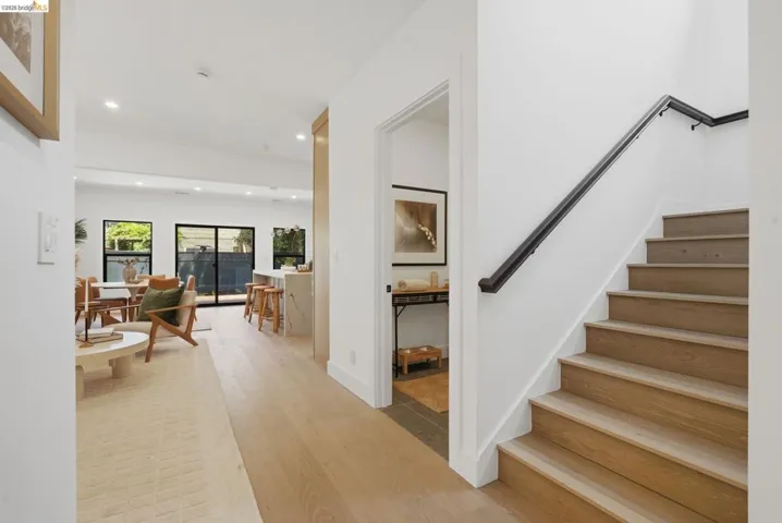 Hardwood flooring extends throughout this open-concept main level, featuring recessed lighting and a contemporary staircase with a dark railing