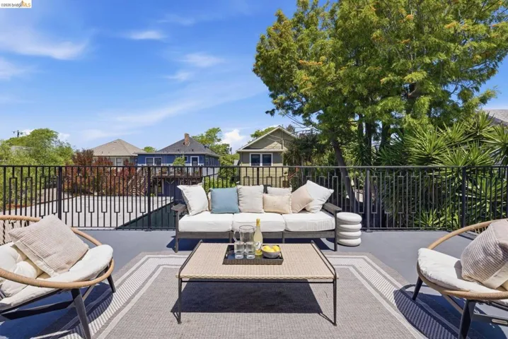 Rooftop terrace featuring a durable black railing system, a textured area rug, and mature landscaping providing natural screening