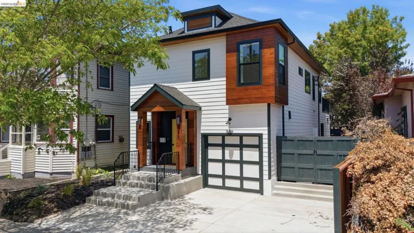 Contemporary exterior featuring white horizontal siding, dark trim windows, and a wood-paneled accent bay
