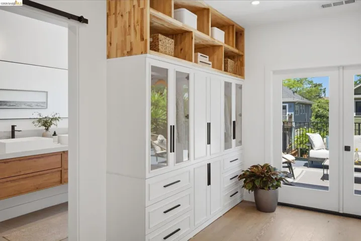 Built-in custom cabinetry with frosted glass doors, light wood shelving, and matte black hardware