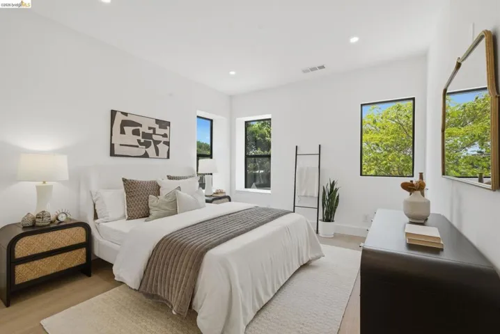 Spacious room featuring light wood-finish flooring, recessed lighting, and white walls