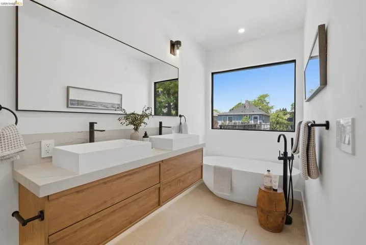 Contemporary bathroom featuring a large picture window, freestanding soaking tub, and a dual vanity with rectangular vessel sinks