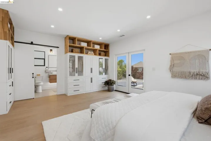 Light wood-finish flooring extending into a private bathroom with a sliding barn door