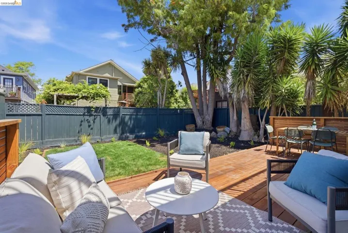 Backyard featuring a wooden deck, a manicured lawn, and mature trees