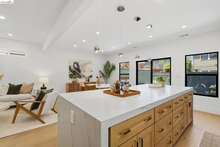 Kitchen island featuring a waterfall-edge countertop and light wood-finish cabinetry