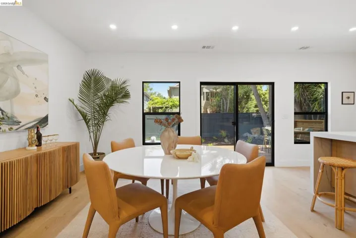 Bright dining area featuring wood-finish flooring, recessed lighting, a built-in wood-slat buffet, and multiple black-framed windows and sliding glass doors