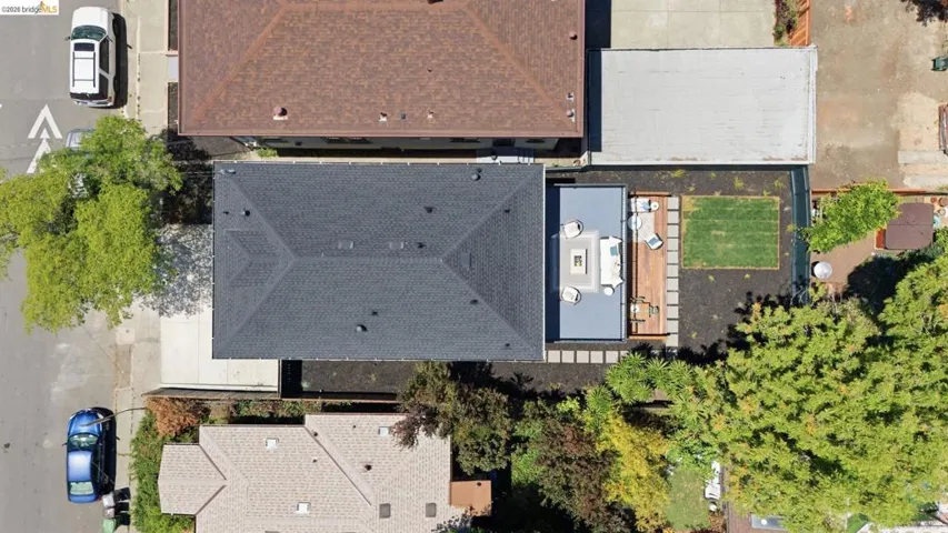 Aerial perspective showcasing a dark shingle roof, a modern outdoor living area, a wooden deck, and a manicured lawn