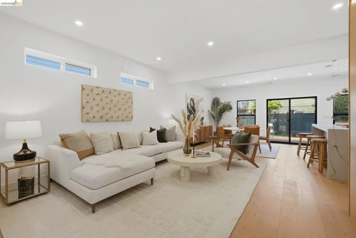 Open-concept living area featuring light wood-finish flooring, white walls, recessed lighting, and clerestory windows