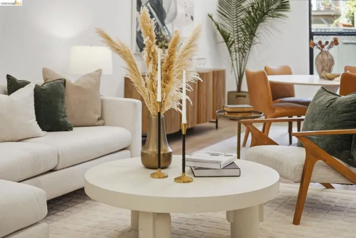 Open-concept living space featuring light-toned walls, wood-finish flooring, and a round coffee table