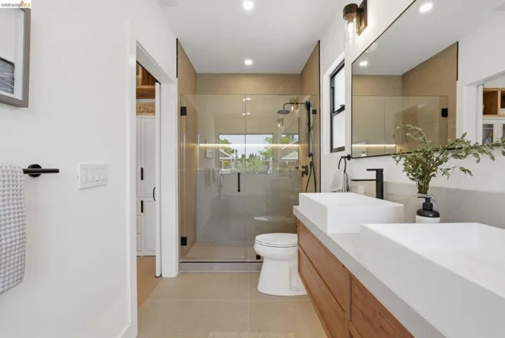 Contemporary bathroom featuring a dual vanity with rectangular vessel sinks, a glass-enclosed shower, and a built-in toilet
