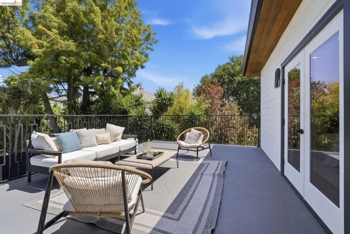Spacious outdoor deck featuring a dark gray surface, black metal railing, and a white exterior wall
