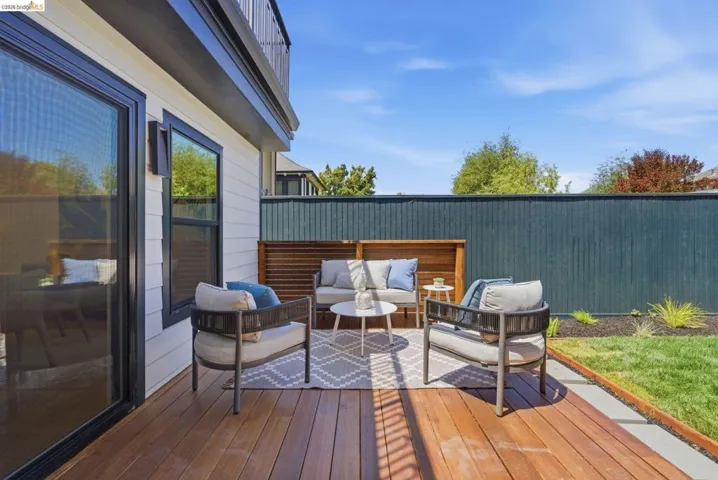Outdoor deck area featuring plank flooring and a dark privacy fence