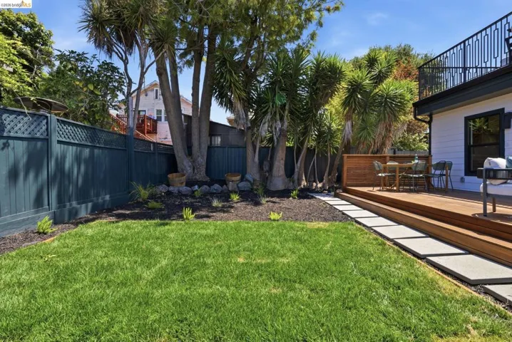 Expansive backyard featuring a lush lawn, raised wood deck, and modern paver pathway