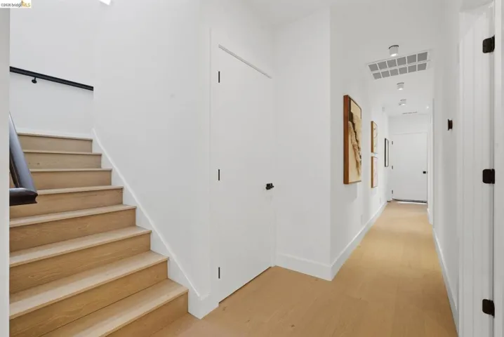 Hallway featuring light wood-finish flooring, white walls, and recessed lighting