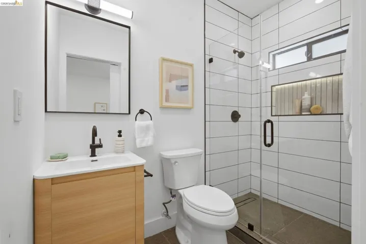 Contemporary bathroom featuring a glass-enclosed shower with white subway tile, an illuminated shower niche, and a horizontal window