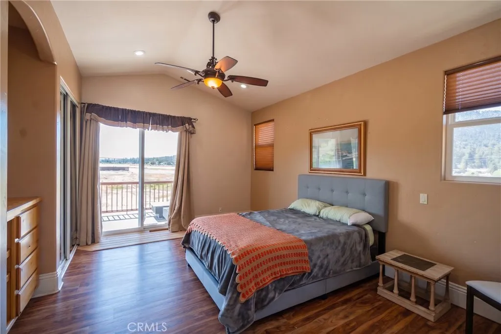 Spacious master bedroom featuring dual closets, private balcony access, and picturesque views of the lake and mountains.