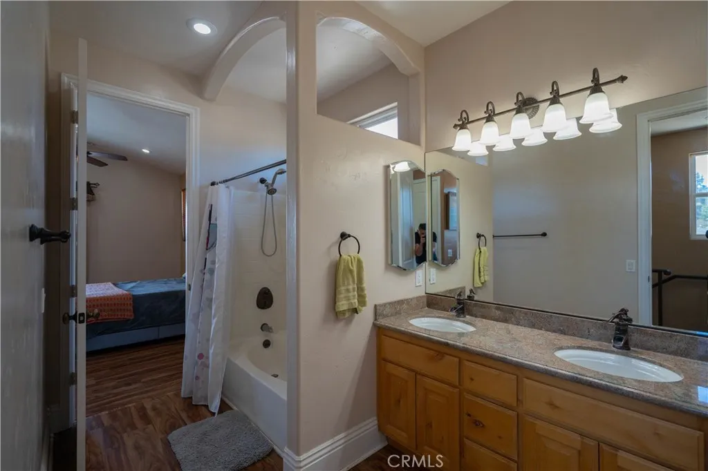 This upstairs bathroom features a dual-sink vanity, a full bathtub, a rain showerhead, a private water closet, and extensive built-in storage.