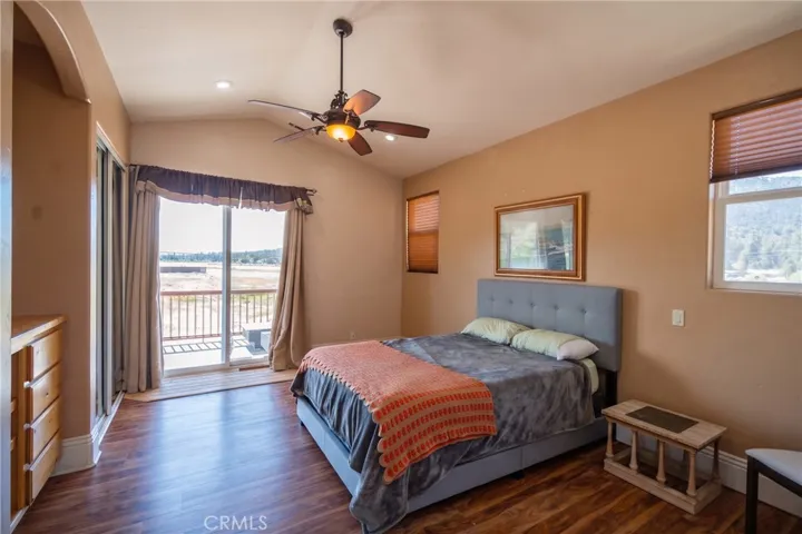 Spacious master bedroom featuring dual closets, private balcony access, and picturesque views of the lake and mountains.