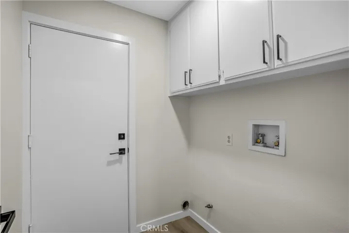 The laundry area offers convenient washer and dryer hookups, overhead cabinet storage, updated flooring, and a clean, functional layout.