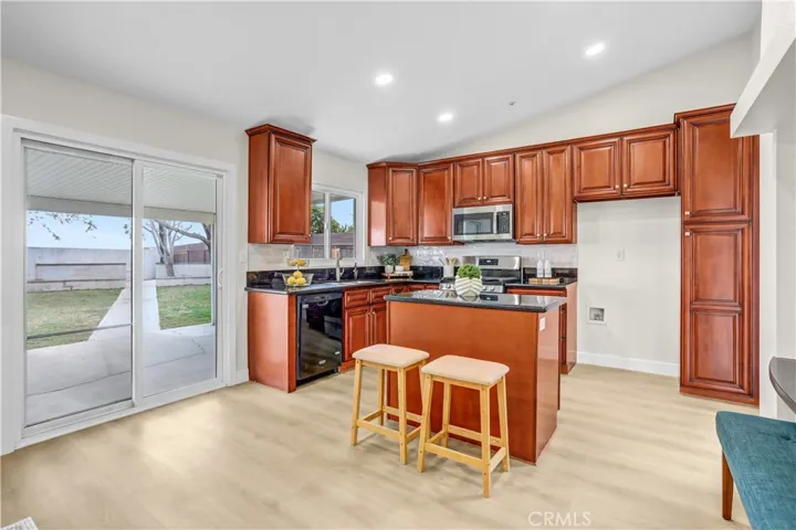 The kitchen features rich wood cabinetry, granite countertops, stainless steel appliances, and a convenient island with bar seating.