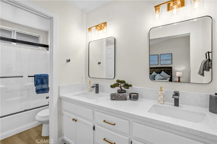 The updated bathroom features Quartz countertop, dual sinks, modern mirrors, stylish lighting, and a clean refreshed look.