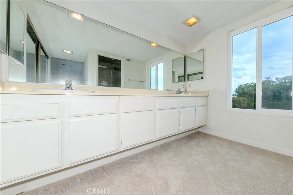 Two sink vanity and large mirrored wardrobe closet in oversized primary bedroom.