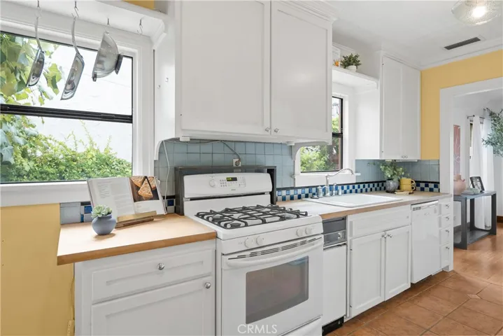 Light and bright kitchen with white cabinetry and butcher block countertops.