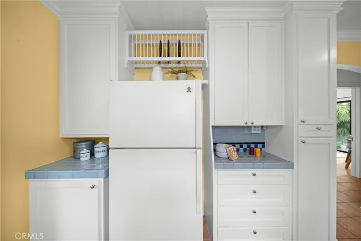 The fridge wall offers more cabinetry, a fun blue tile and slots for colorful plates.