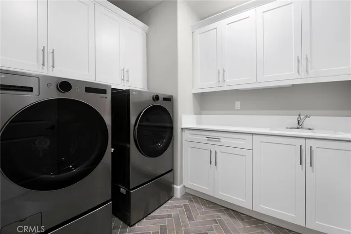 Convenient upstairs laundry with herringbone designer tile and an abundance of cabinetry