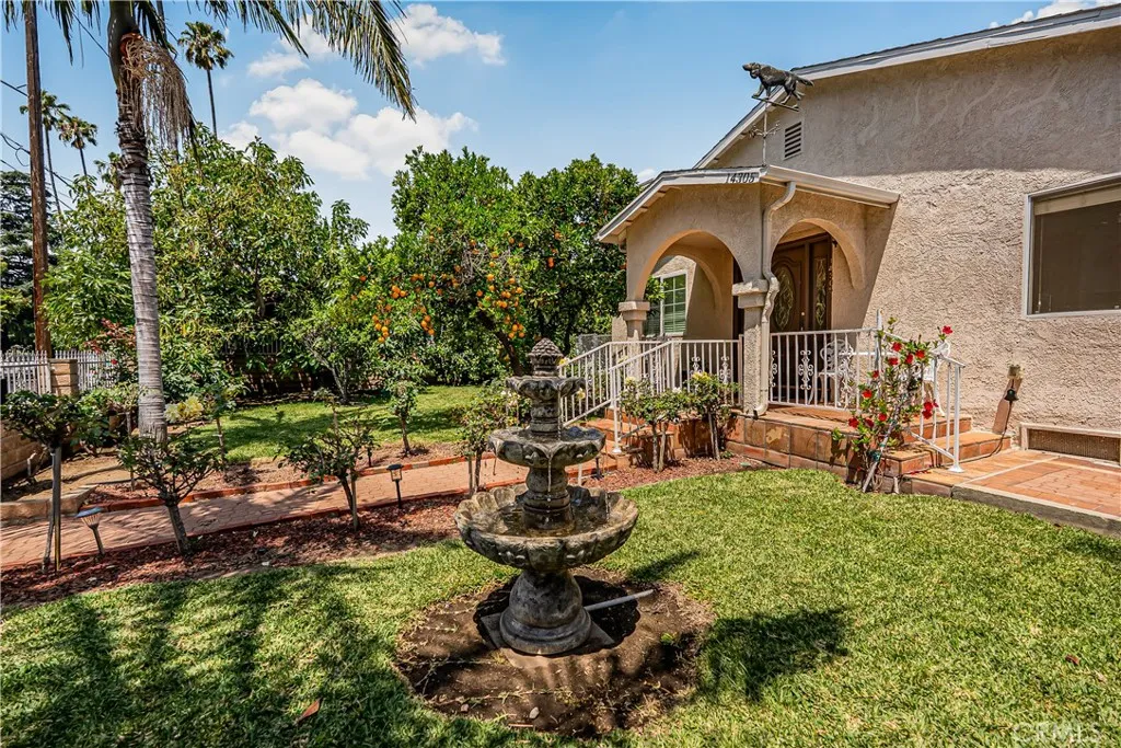 FRONT LAWN WITH MULTIPLE FRUIT BEARING TREES AND A SHOOTING FOUNTAIN