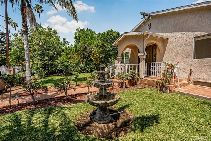 FRONT LAWN WITH MULTIPLE FRUIT BEARING TREES AND A SHOOTING FOUNTAIN
