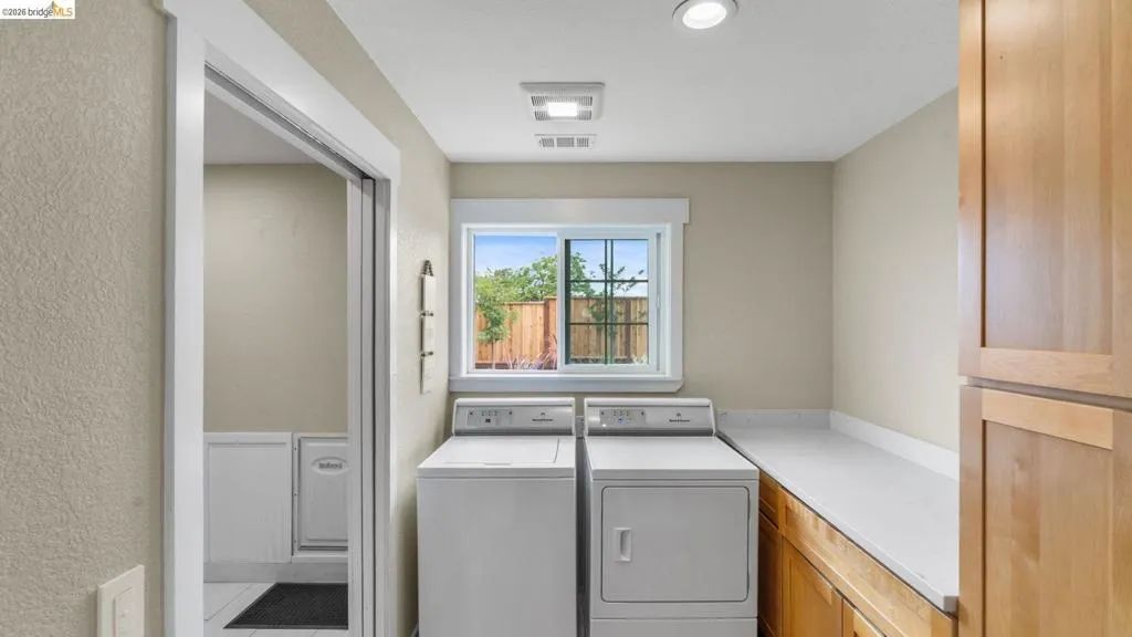 Dedicated laundry area featuring a window, built-in cabinetry, and a substantial countertop